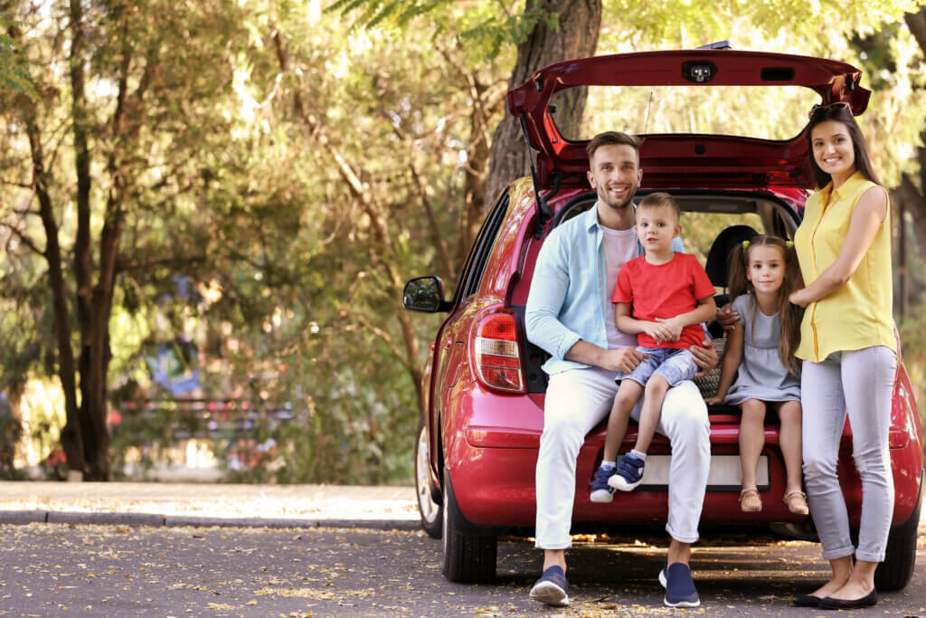 young couple with two young children sitting in vehicle hatchback