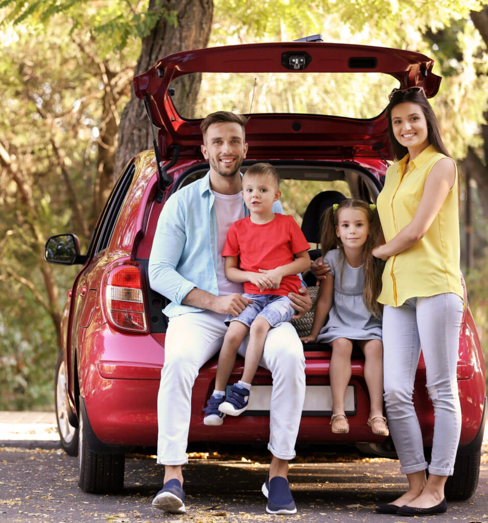 young couple with two young children sitting in vehicle hatchback