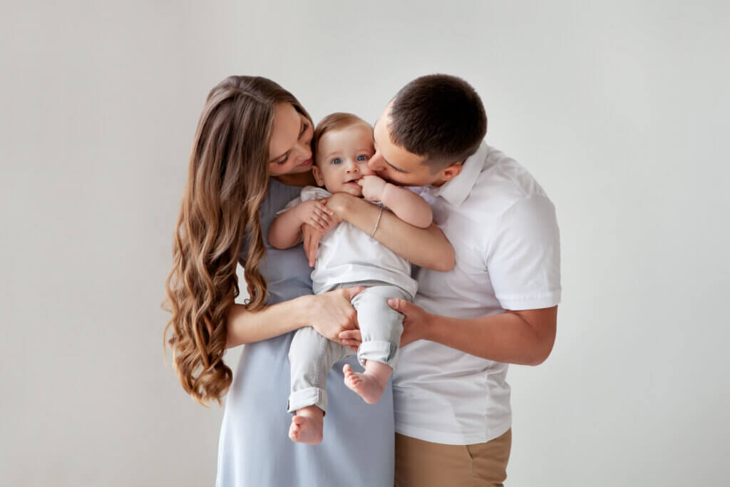 young couple kissing baby