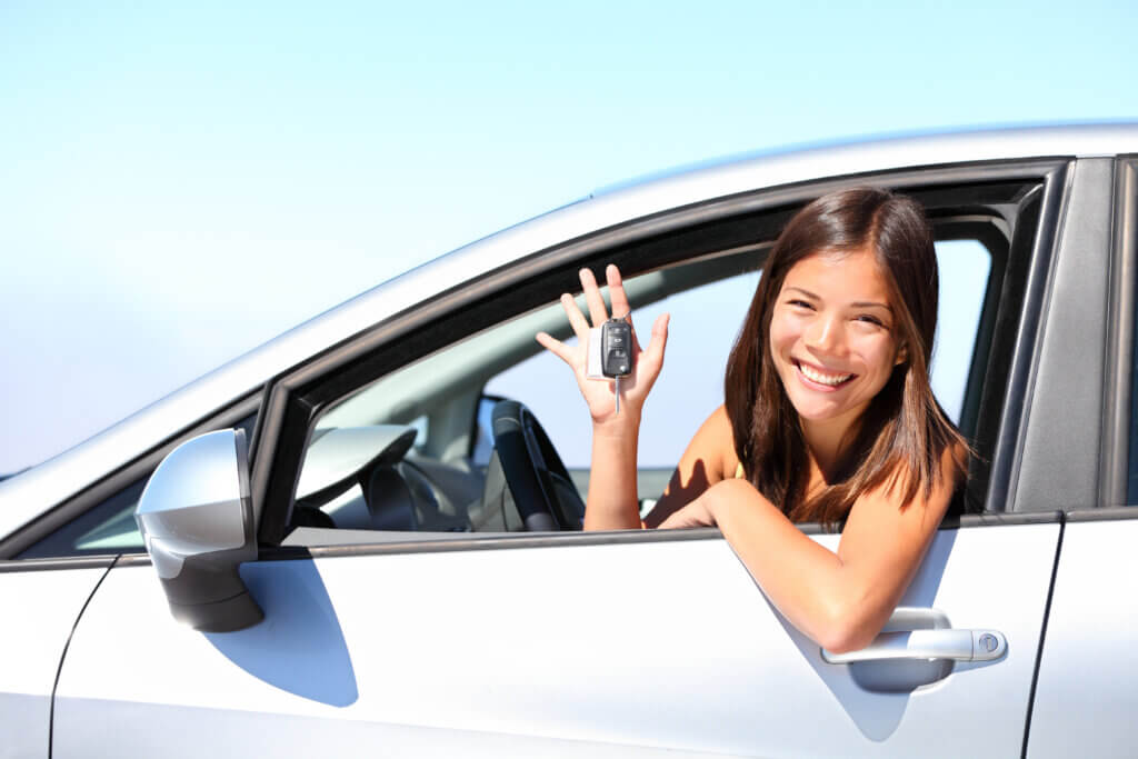 young woman in light colored sedan holding keys