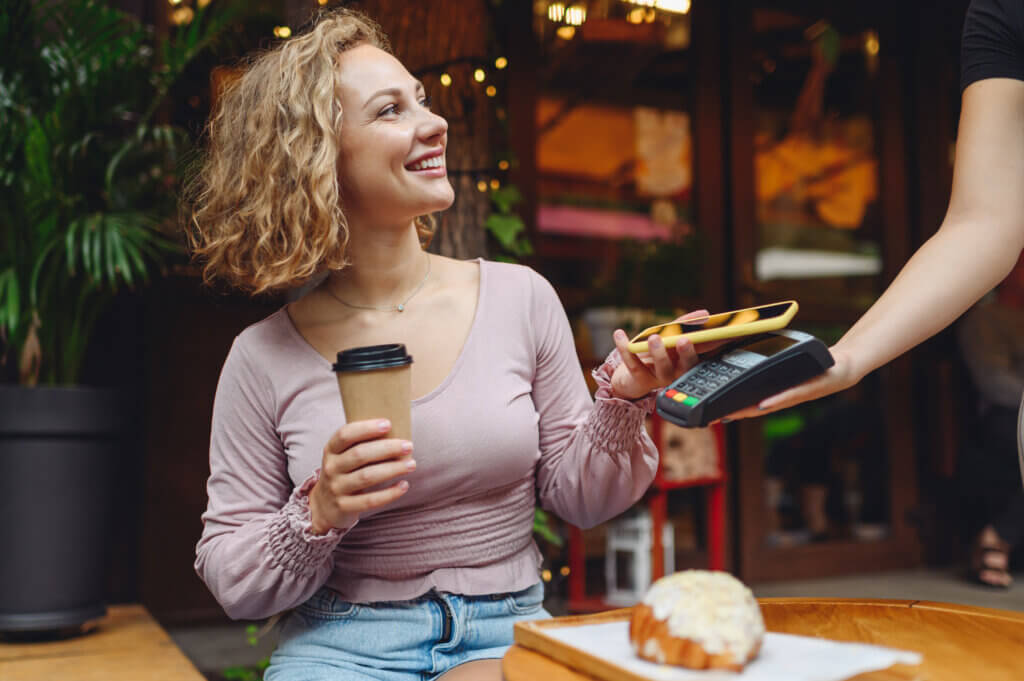 young woman with coffee making mobile payment